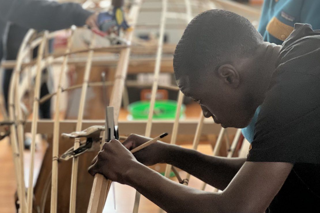 photo of a young man working on a wooden canoe