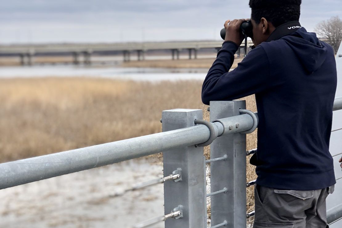 young man looking through binoculars at a wildlife refuge